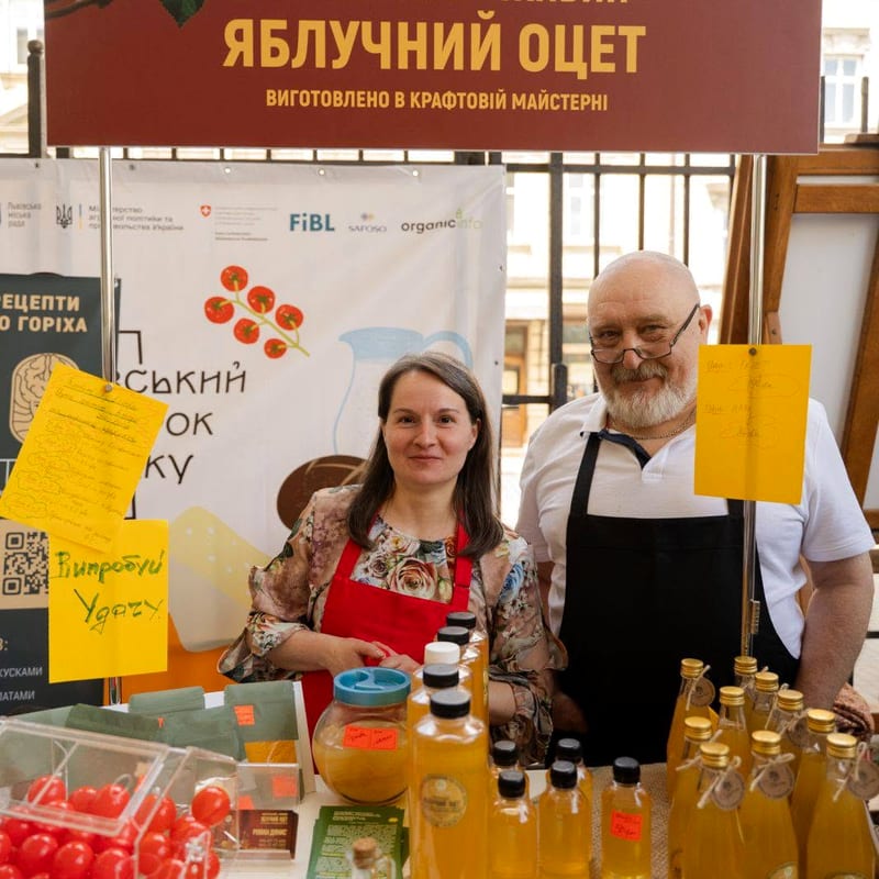 Роман (праворуч, в окулярах і чорному фартусі) за стендом майстерні «Струмок» із пляшками оцту на Львівському ярмарку смаку